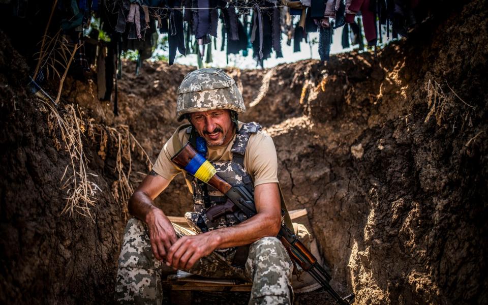 A Ukrainian soldier takes a moment in a trench near the front line