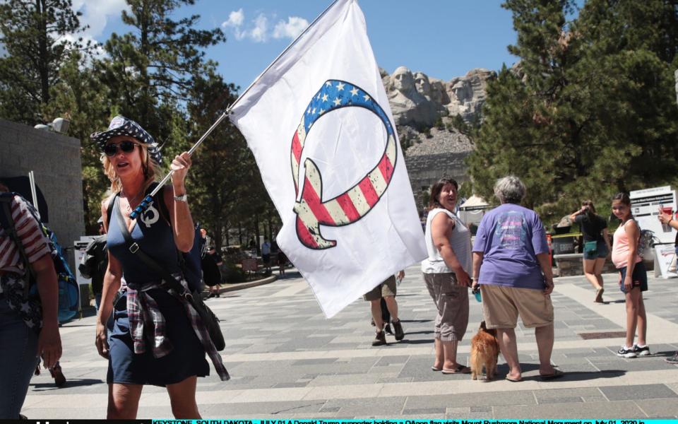 A Donald Trump supporter holding a QAnon flag visits Mount Rushmore National Monument on July 01, 2020 in Keystone, South Dakota - Scott Olson/Getty