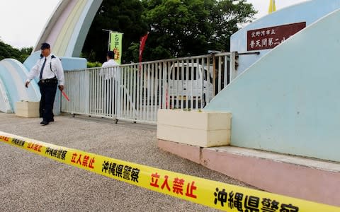 A Japanese policeman stands guard at the entrance gate of the elementary school in Ginowan, Okinawa - Credit: AFP