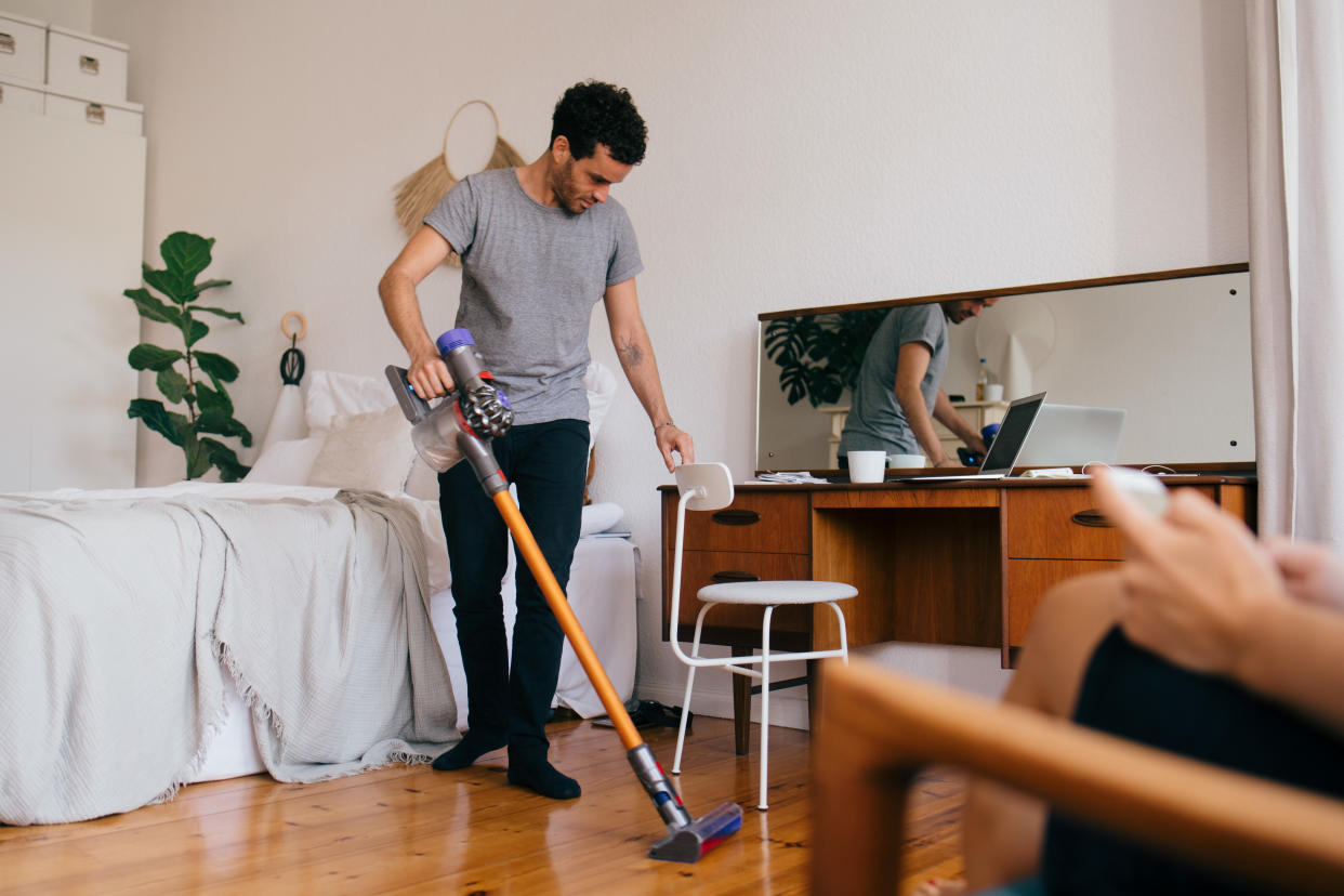 photo of a man vacuuming a bedroom