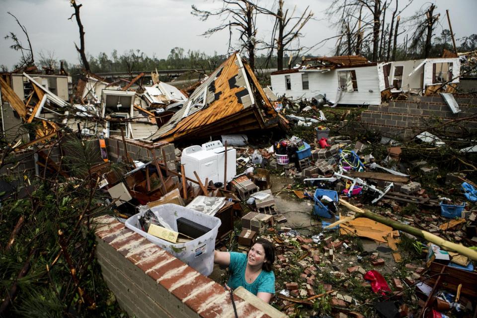 Jodi Walls pushes a box of belongings out of a friends house while cleaning up after a large tornado made its way along Clayton Ave in Tupelo, Miss., Monday, April 28, 2014. (AP Photo/The Commercial Appeal, Brad Vest)