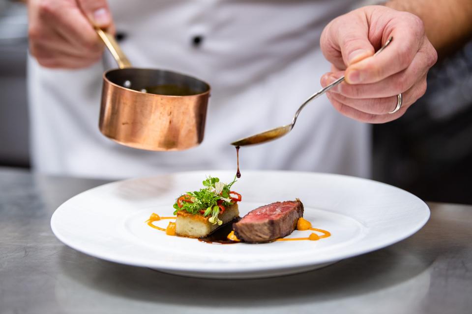 A chef spoons sauce over Miyazaki A-5 beef, potato rosti and Romesco, one of the courses on the Chef's Degustation Menu at Victoria & Albert's.