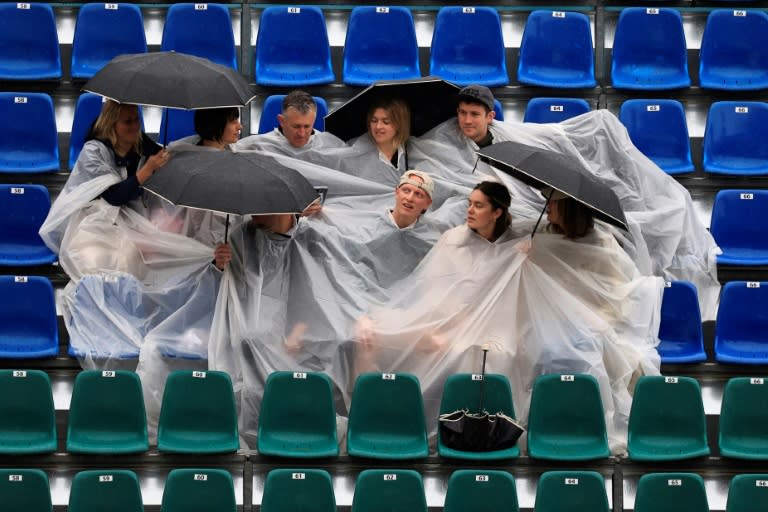 Des spectateurs tentent de s'abriter de la pluie dans une tribune du Monte Carlo Country Club le9 avril 2024. Les premiers matches de la journée ont débuté avec deux heures et demie de retard sur le programme (Valery HACHE)