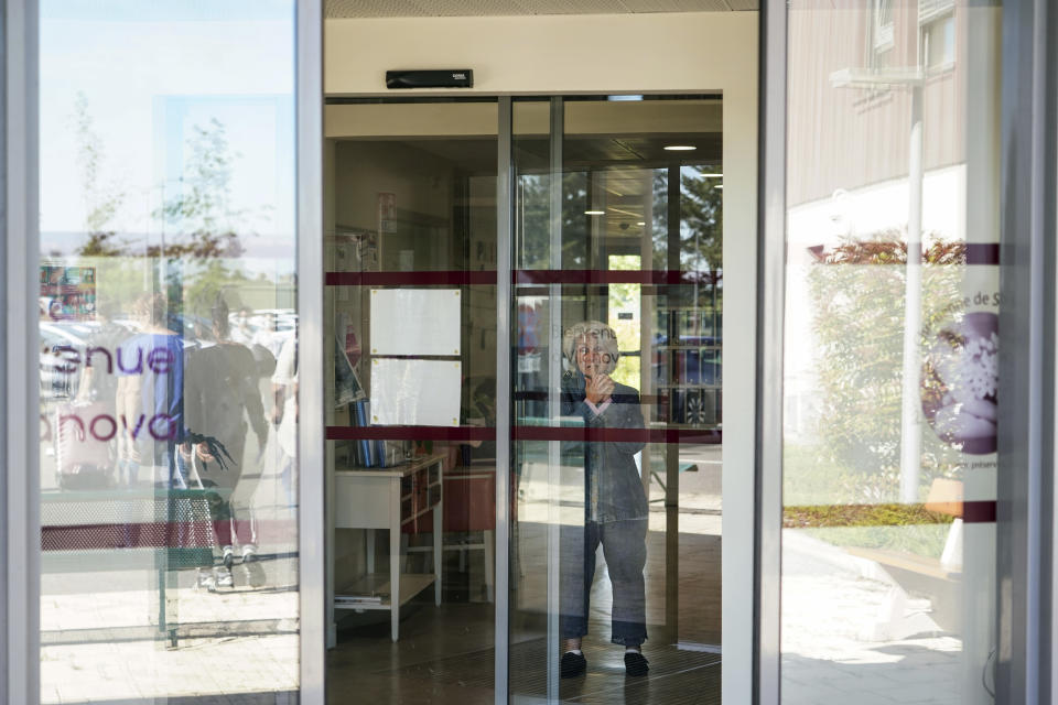 A resident watches nurses leaving the Vilanova nursing home in Corbas, near Lyon, central France, Monday, May 4, 2020. For 47 days and nights, staff and the 106 residents of the Vilanova nursing home waited out the coronavirus storm together, while the illness killed tens of thousands of people in other homes across Europe, including more than 9,000 in France. Because staff and residents were locked in together, Vilanova didn't have to confine people to their rooms like other homes to shield them from the risk of infection brought in from outside. (AP Photo/Laurent Cipriani)