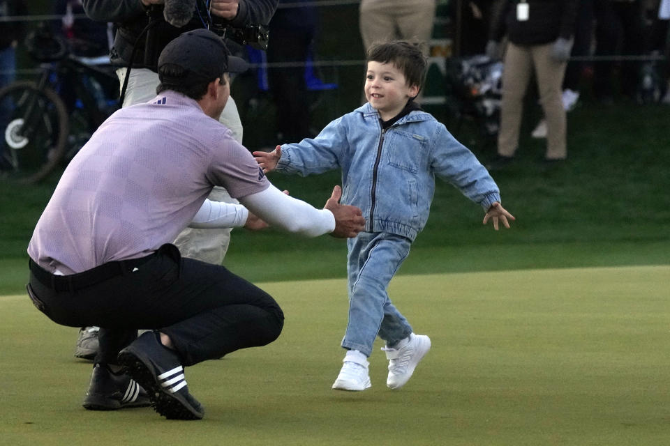 Nick Taylor, left, of Canada, is greeted by his son Charlie, 4, right, after the golfer's two-hole playoff win against Charley Hoffman during the final round of the Phoenix Open golf tournament Sunday, Feb. 11, 2024, in Scottsdale, Ariz. (AP Photo/Ross D. Franklin)