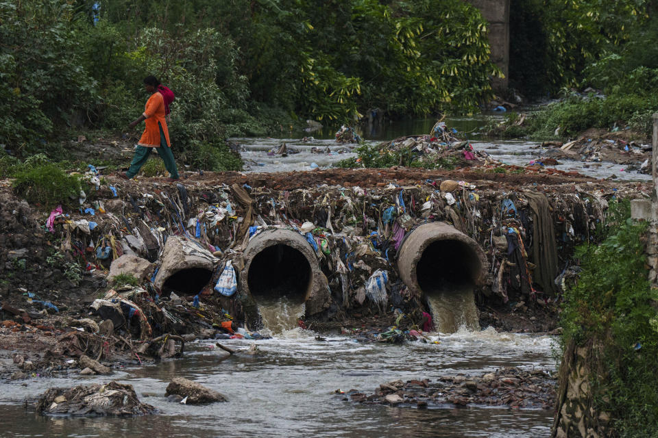 Una mujer camina sobre unas tuberías que desaguan al río Bagmati en Katmandú, Nepal, el miércoles 1 de junio de 2022. Mala Kharel, miembro de un comité gubernamental que se creó para ayudar a limpiar el río. dijo que, a lo largo de los años, la campaña ha logrado recolectar alrededor del 80% de la basura en la orilla del río. Pero es una realidad que los esfuerzos se quedan cortos. (AP Foto/Niranjan Shrestha)