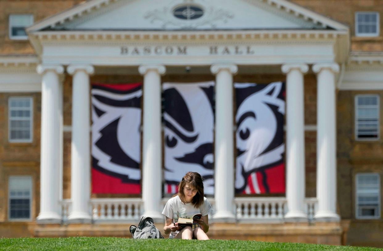 University of Wisconsin-Madison student Jordyn Ginestra, a junior from St. Louis majoring in English, reads Moby Dick outside Boscom Hall on campus in Madison on Tuesday, May 16, 2023. The incoming class this fall tipped the scale and UW-Madison now enrolls more than 50,000 students.