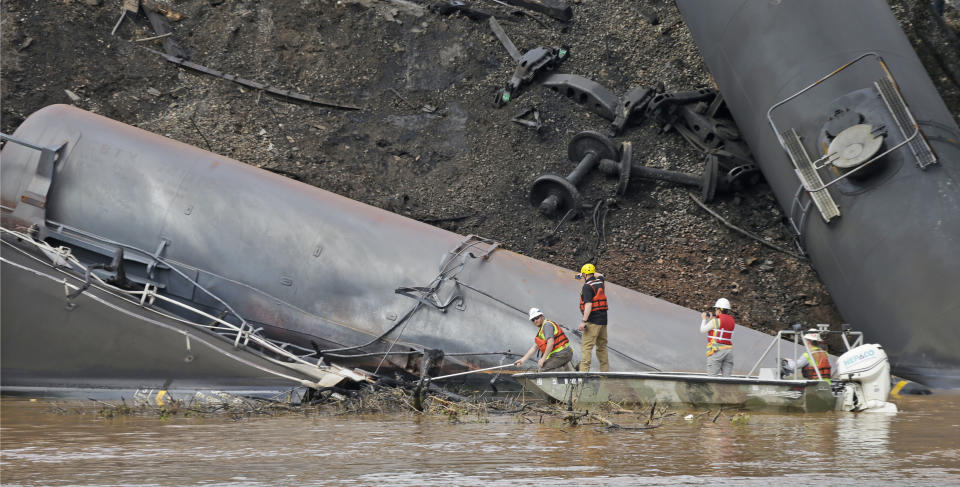 Survey crews in boats look over tanker cars as workers remove damaged tanker cars along the tracks where several CSX tanker cars carrying crude oil derailed and caught fire along the James River near downtown Lynchburg, Va., Thursday, May 1, 2014. Virginia state officials were still trying Thursday to determine the environmental impact of the train derailment. (AP Photo/Steve Helber)