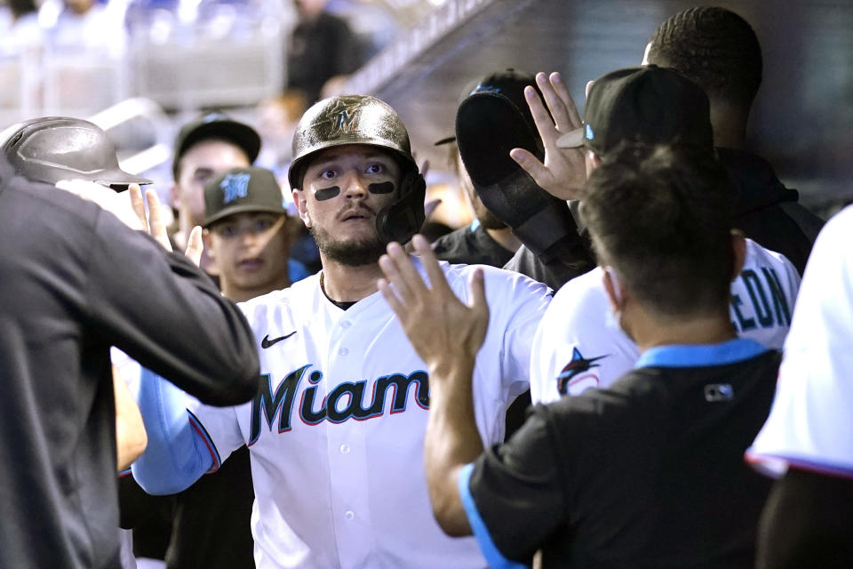 Miami Marlins' Miguel Rojas is congratulated in the dugout after scoring on a single hit by Jazz Chisholm Jr. during the third inning of a baseball game against the New York Mets, Thursday, Aug. 5, 2021, in Miami. (AP Photo/Lynne Sladky)