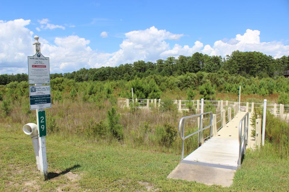 The fishing pier on North Lake in Boiling Spring Lakes sits empty and overtaken by weeds on August 9.