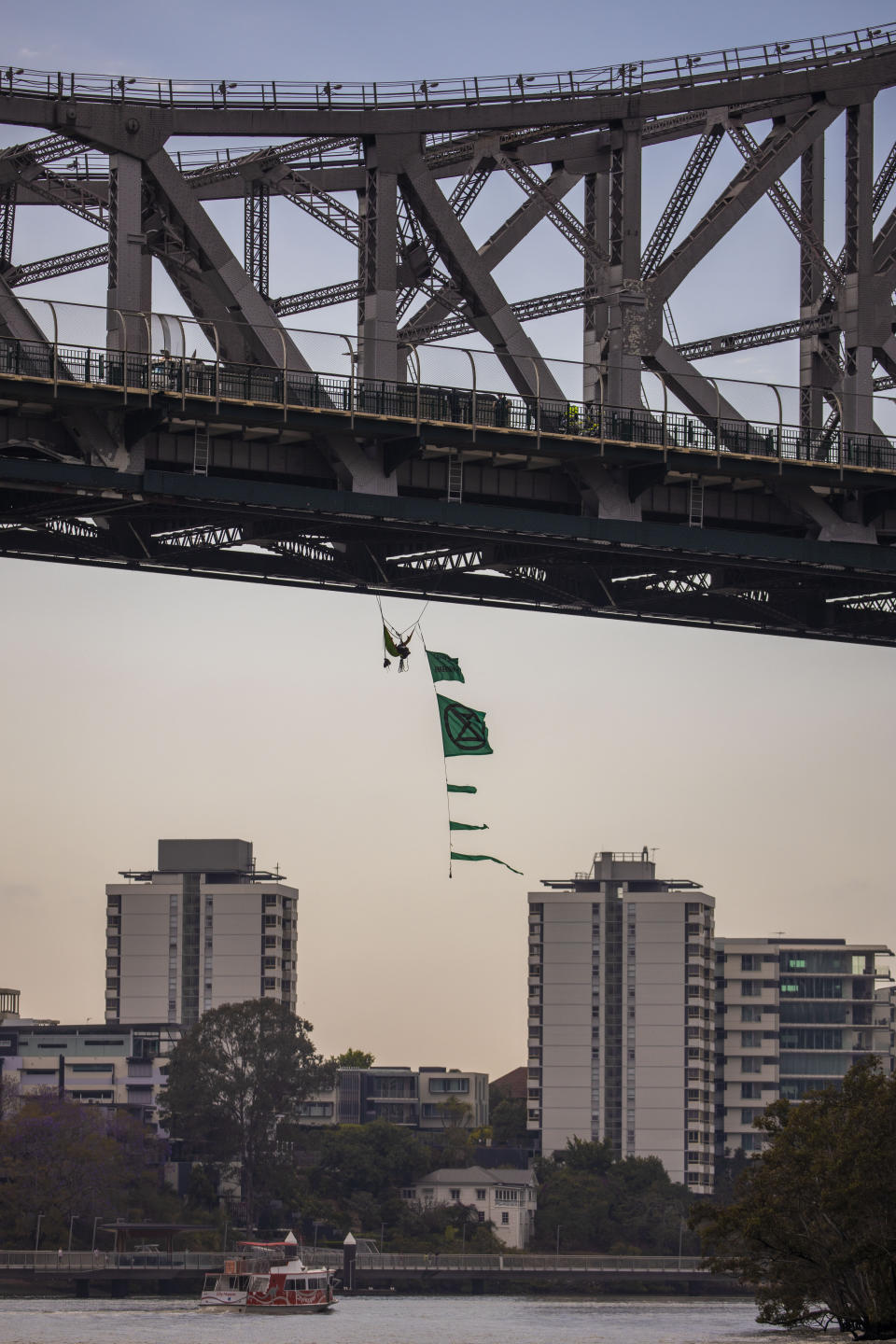 The activist hangs from the bridge with a series of flags. Source: AAP