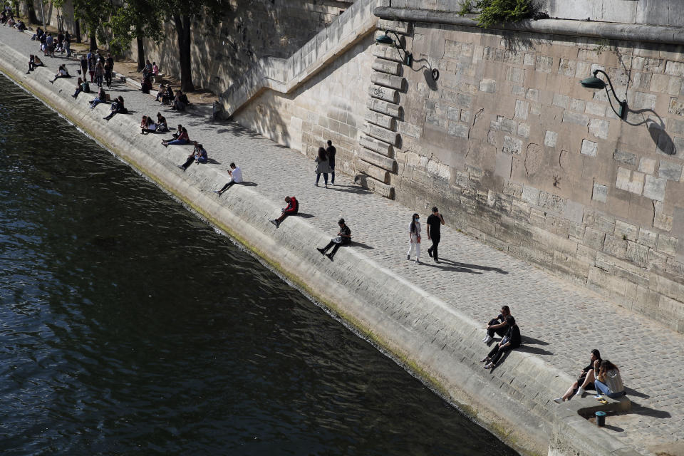 Parisians sit in the sun along the Seine river banks in Paris, Saturday, May 23, 2020 as France gradually lifts its COVID-19 lockdown. (AP Photo/Francois Mori)