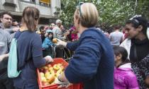 Helpers distribute fruit to migrants wait in front of the State Office for Health and Social Affairs (LaGeSo), in Berlin, Germany, September 3, 2015. REUTERS/Hannibal Hanschke