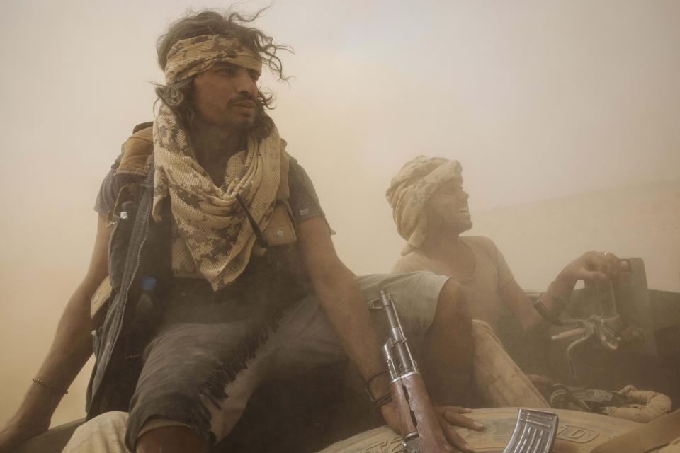 Yemeni fighters backed by the Saudi-led coalition ride on the back of an armored vehicle as they leave the front lines near Marib, Yemen, Saturday, June 19, 2021. (AP Photo/Nariman El-Mofty)