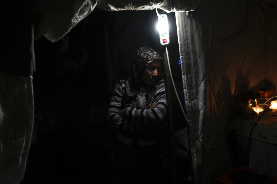 A woman stands next to a lamp inside a tent in Antakya, southern Turkey, Friday, Jan. 12, 2014. A year after a powerful earthquake hit the region, some families who do not qualify for container homes are sheltering in tents, too afraid to return to homes that authorities have listed as being slightly damaged. (AP Photo/Khalil Hamra)