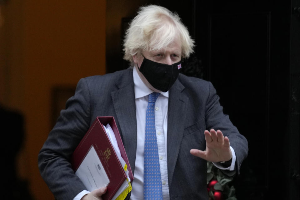 Britain's Prime Minister Boris Johnson waves as he leaves 10 Downing Street to attend the weekly Prime Minister's Questions at the Houses of Parliament, in London, Wednesday, Dec. 15, 2021. British lawmakers have voted to approve new restrictions to curb the spread of the omicron coronavirus variant. The House of Commons approved measures ordering masks to be worn indoors in England and requiring proof of vaccination or a negative test to enter nightclubs and large crowded events. (AP Photo/Kirsty Wigglesworth)