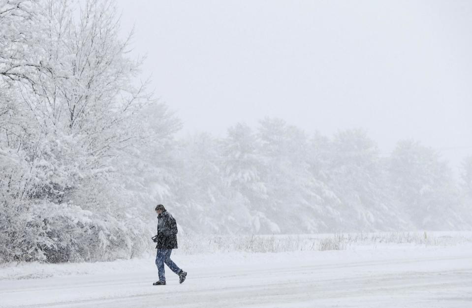 A motorist walks back to his car after helping a motorist stuck in a snow drift, Sunday, Jan. 5, 2014, in Zionsville, Ind. Snow that began in parts of Indiana Saturday night picked up intensity after dawn Sunday with several inches of snow on the ground by midmorning and more on the way. (AP Photo/Darron Cummings)