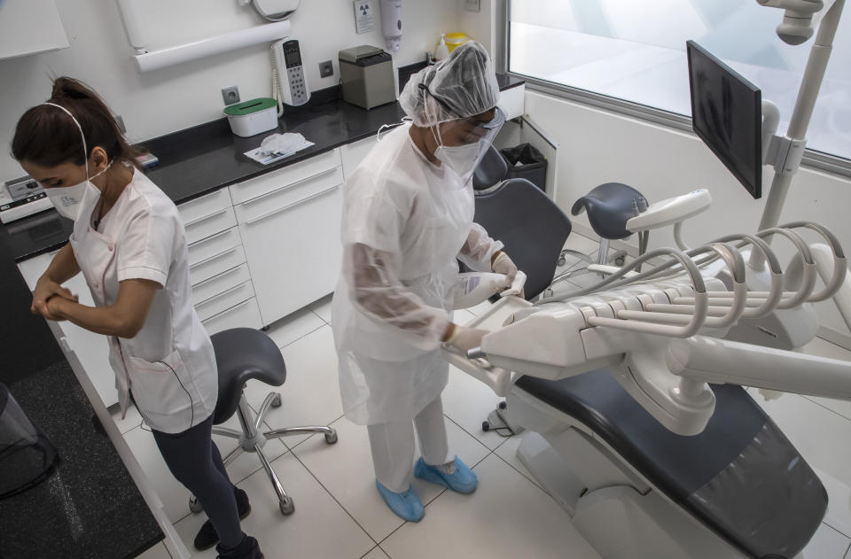 In this photo taken on Wednesday, May 13, 2020, dentist Sabrine Jendoubi, left, and her assistant Margot Daussat prepare for a dental appointment at a dental office in Paris. Those with toothache that suffered through France's two-month lockdown, finally have hope to end the pain. Dental practices are cautiously re-opening and non-emergency dentist appointments are now permitted around the country, as the French government eased confinement restrictions from Monday. (AP Photo/Michel Euler)