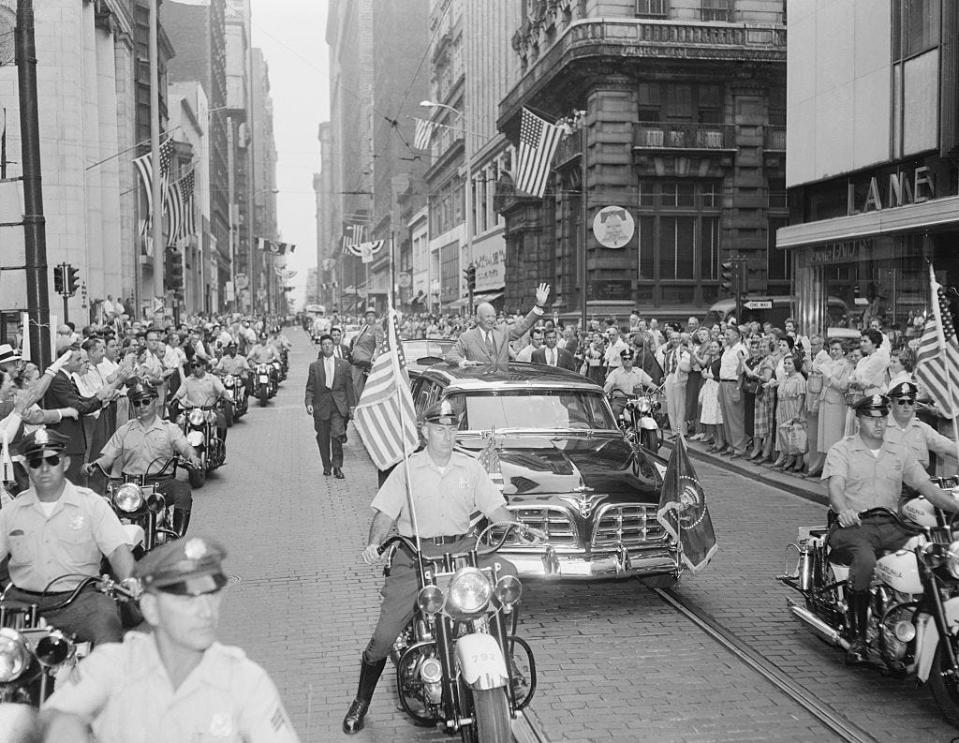 President Dwight Eisenhower waves from the presidential limousine