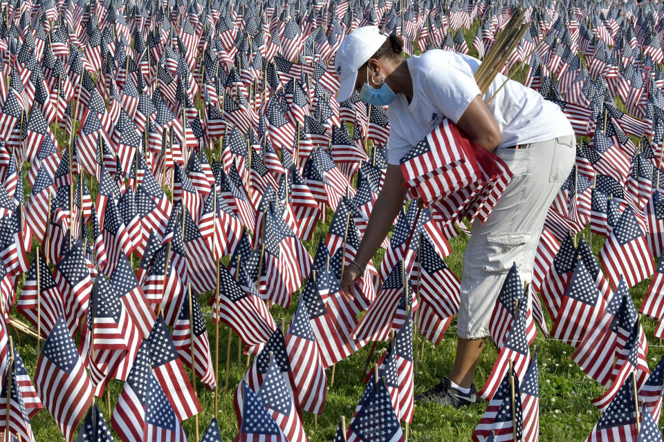 A volunteer places American flags on Boston Common ahead of Memorial Day, Wednesday. May 26, 2021, in Boston. After more than a year of isolation, American veterans are embracing plans for a more traditional Memorial Day. They say wreath-laying ceremonies, barbecues at local vets halls and other familiar events are a welcome chance to reconnect with fellow service members and renew solemn traditions honoring the nation’s war dead. (AP Photo/Josh Reynolds)