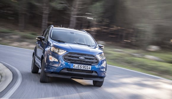 A blue 2018 Ford Ecosport, a small SUV, on a curvy road.