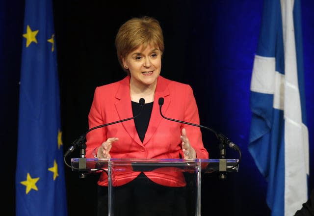 Nicola Sturgeon speaking in front of flags of Scotland and the EU