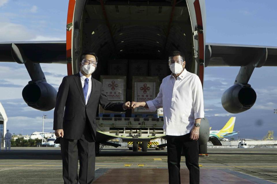 In this photo provided by the Malacanang Presidential Photographers Division, Philippine President Rodrigo Duterte, right, poses with Chinese Ambassador to the Philippines Huang Xilian, second from left, as they stand in front of a military place carrying Sinovac vaccines from China at the Villamor Air Base in Manila, Philippines on Sunday Feb. 28, 2021. The Philippines received its first batch of COVID-19 vaccine Sunday, among the last in Southeast Asia to secure the critical doses despite having the second-highest number of coronavirus infections and deaths in the hard-hit region. (King Rodriguez/Malacanang Presidential Photographers Division via AP)