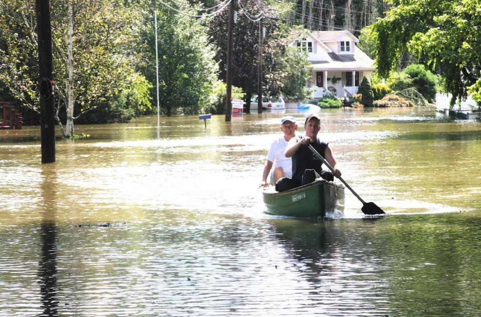 In this 2011 file photo taken in the wake of Hurricane Irene, neighbors Kyle McKiernan, right, and Jim Guilfoyle return from a trip to Guilfoyle's home on Jeffrey Court in West Nyack.