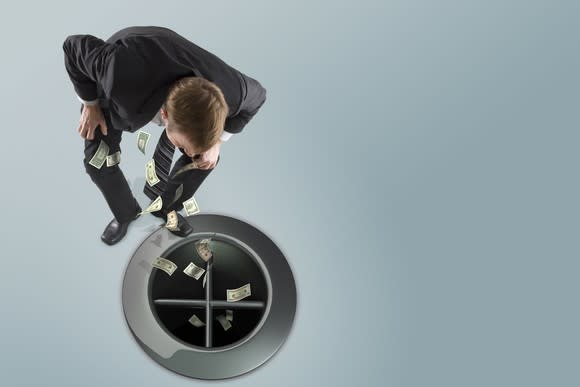 Man in suit watching money go down the drain