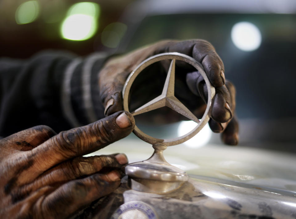 A mechanic replaces a sing on a 1976 Mercedes at a private collector's lot in El Saff city in the Giza, just outside Cairo, Egypt. Friday, April 8, 2022. Egyptian businessman and a classic car collector Mohamed Wahdan says he has accumulated more than 250 vintage, antique and classic cars over the past 20 years. (AP Photo/Amr Nabil)