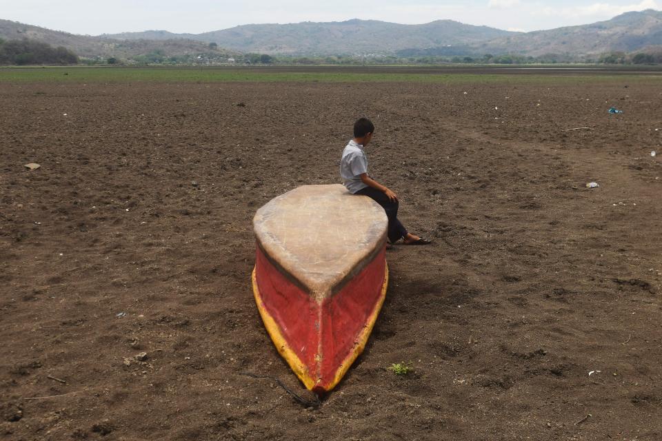 In a photo from May 2017, a boy sits on an abandoned boat on what is left of Guatemala's Lake Atescatempa, which dried up due to drought and high temperatures.&nbsp; (Photo: MARVIN RECINOS via Getty Images)