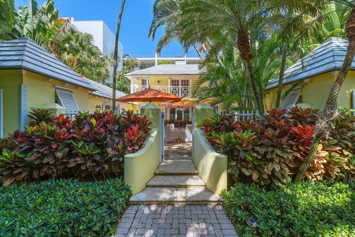 The yellow Bermuda-style house has pitched tile roofs and a footprint shaped like a squared-off horseshoe. Architect Belford Shoumate designed the house in the 1930s and used it as his family residence and professional offices.