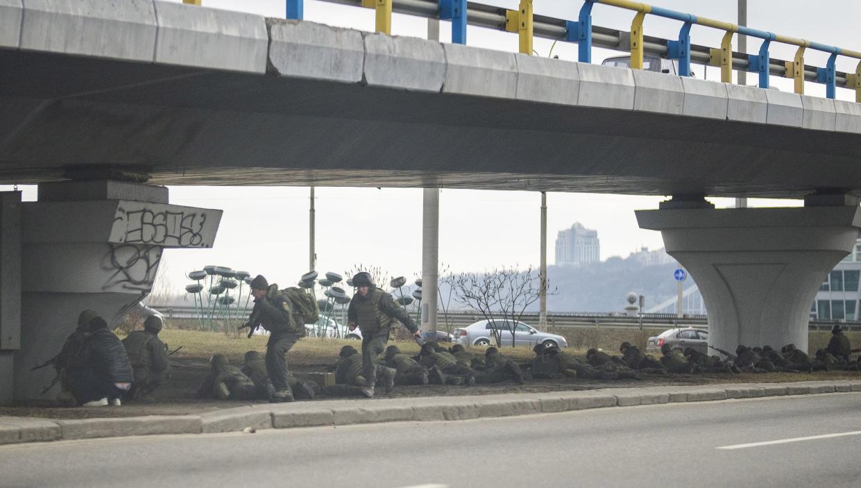 Ukrainian soldiers take position under a bridge during crossfire inside the city of Kyiv, Ukraine, Friday, Feb. 25, 2022. Russia pressed its invasion of Ukraine to the outskirts of the capital Friday after unleashing airstrikes on cities and military bases and sending in troops and tanks from three sides in an attack that could rewrite the global post-Cold War security order.
