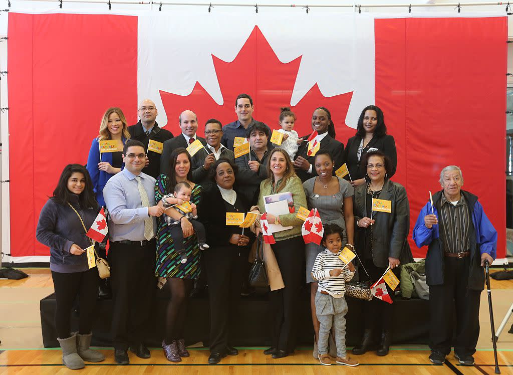 A group of new Canadians who originate from countries that are competing in Pan Am Games pose for pictures at the Pan Am Games celebration.