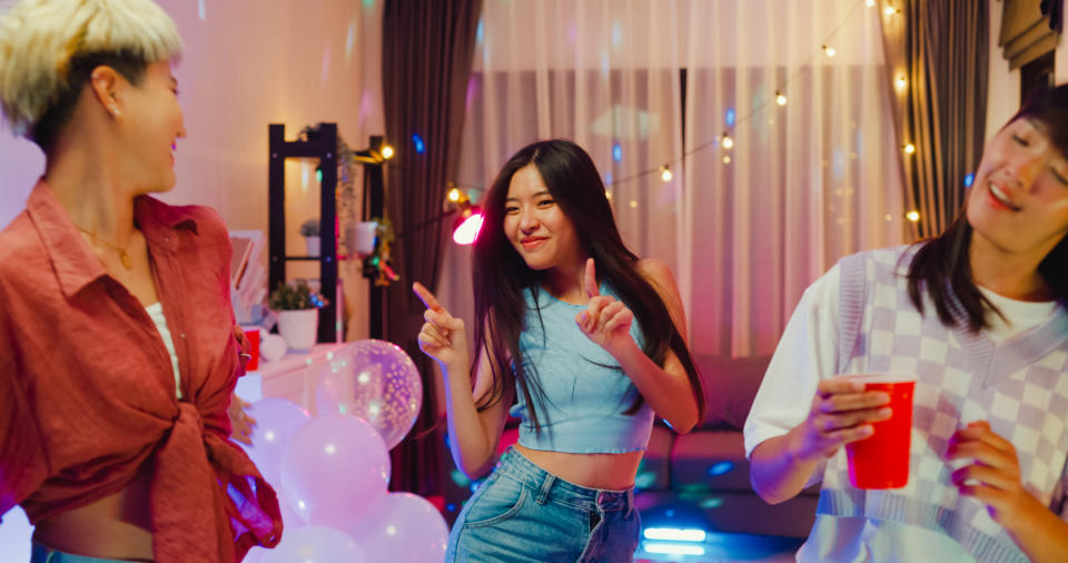 Young Asian female friends dancing having fun at colorful house party at night. Lifestyle together concept.