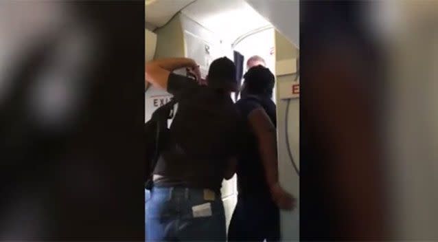 The man tries to push past a flight attendant onboard an American Airlines flight.