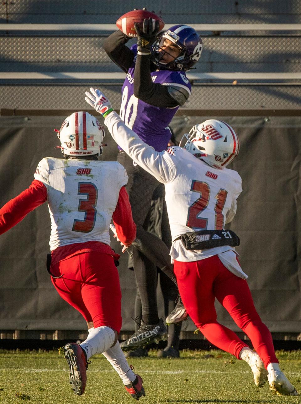 Holy Cross wide receiver Jalen Coker hauls in a 35-yard touchdown pass with Sacred Heart defenders Shamere Collins and Quinn Hart closing in during the final seconds of Saturday's playoff win.