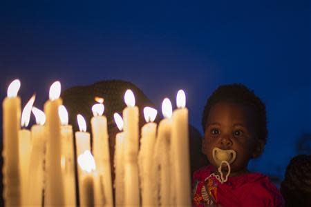 An child stares into candles lit as a memorial outside the Nelson Mandela house in the Houghton Estates neighbourhood of Johannesburg, December 7, 2013. REUTERS/Adrees Latif