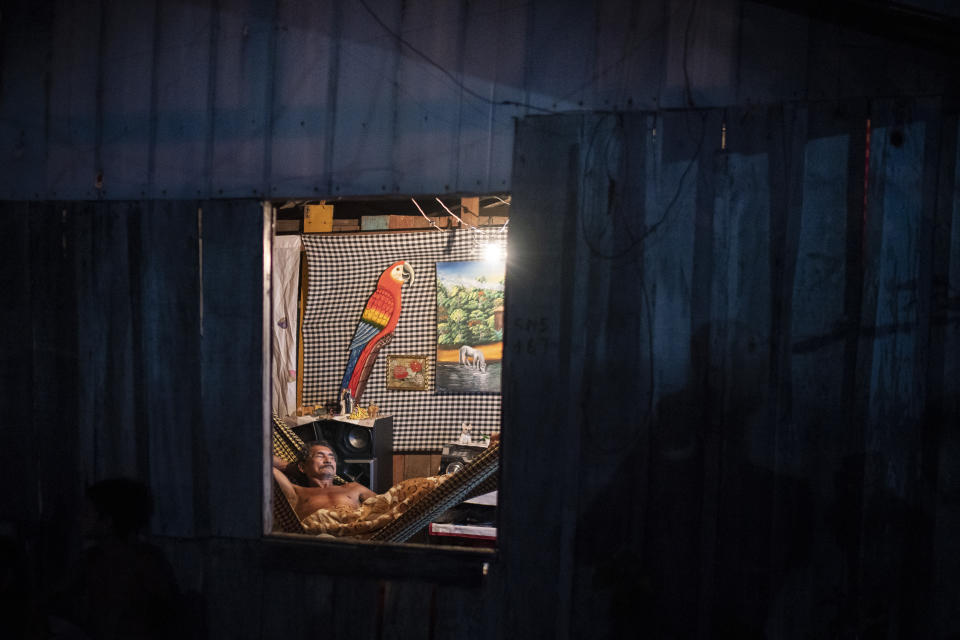 A man rests in a hammock inside his home at the Park of Indigenous Nations community, where many residents fell ill with symptoms of the new coronavirus, in Manaus, Brazil, Sunday, May 10, 2020. Per capita, Manaus is Brazil's major city hardest hit by COVID-19. (AP Photo/Felipe Dana)