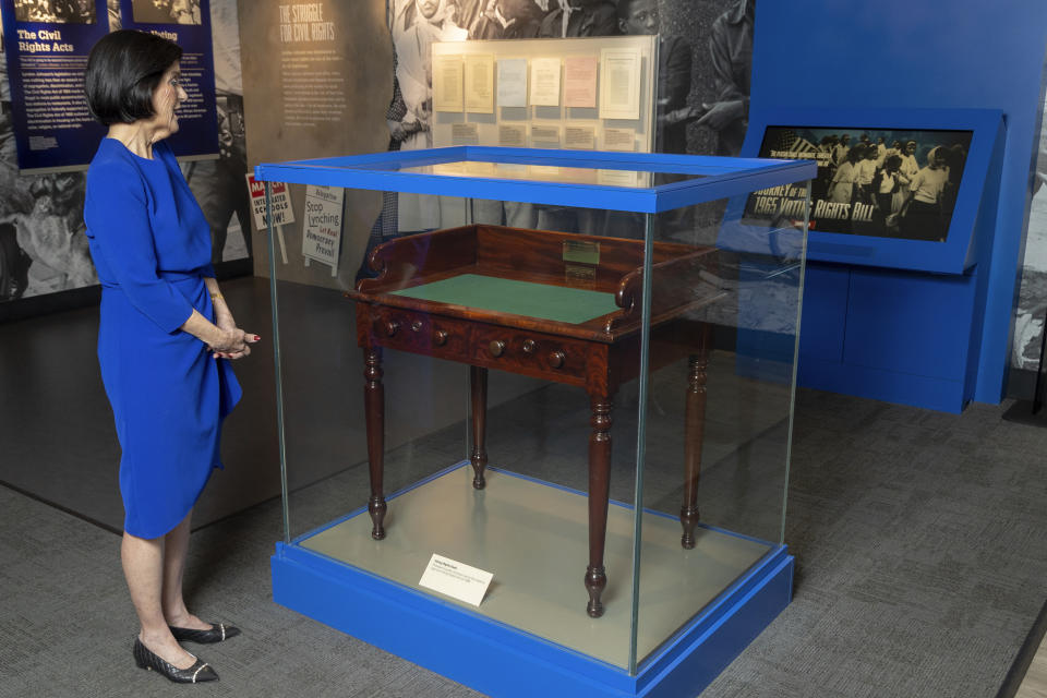 Luci Baines Johnson looks at the desk on May 16, 2023, on display at the LBJ Presidential Library, that President Lyndon B. Johnson sat at in the President's Room at the U.S. Capitol to sign the Voting Rights Act of 1965, on Aug. 6, 1965. (AP Photo/Stephen Spillman)