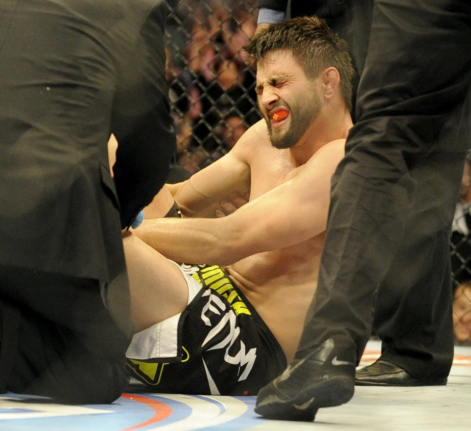 Carlos Condit is tended to by doctors after being injured during a UFC 171 mixed martial arts welterweight bout against Tyron Woodley, Saturday, March. 15, 2014, in Dallas. Woodley won by TKO. (AP Photo/Matt Strasen)