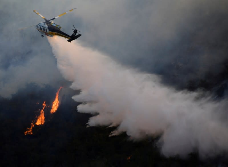 FILE PHOTO: A firefighting helicopter makes a water drop on the Getty Fire as it burns in the hills of West Los Angeles, California