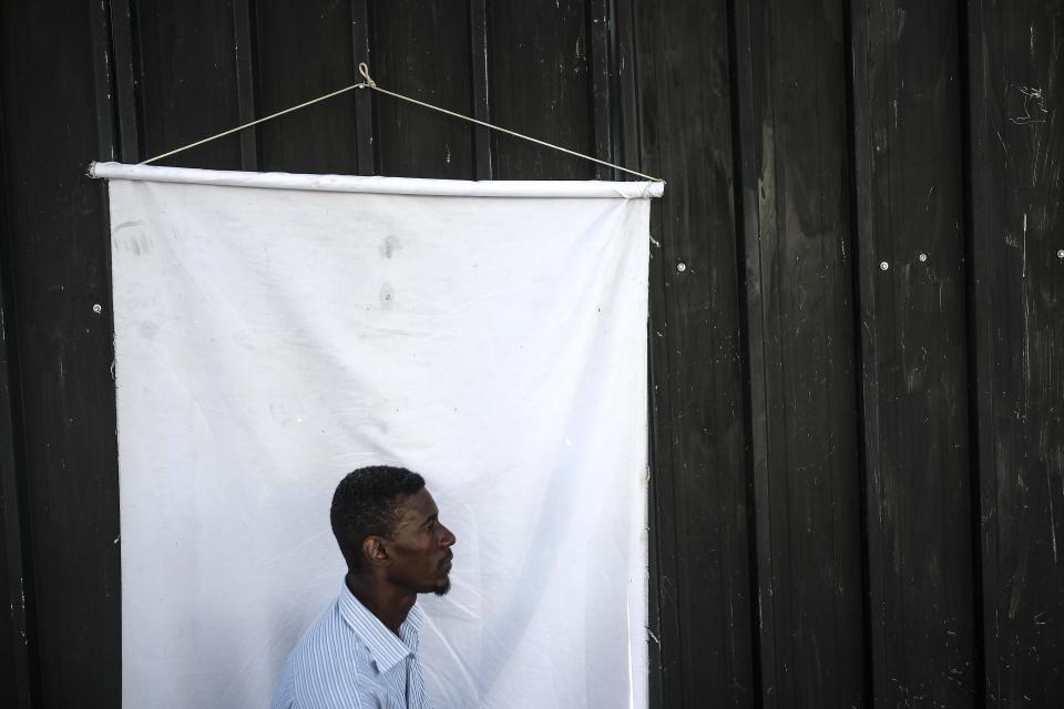 A man poses for an ID photo in an improvised photo studio outside the General Directorate of Migration in Santo Domingo, Dominican Republic, Monday, Nov. 22, 2021. The government has repeatedly said it treats migrants humanely. President Luis Abinader recently told the United Nations that his country had borne the burden of dealing with the ripples of Haiti’s crises on its own, without much help from the rest of the world. (AP Photo/Matias Delacroix)