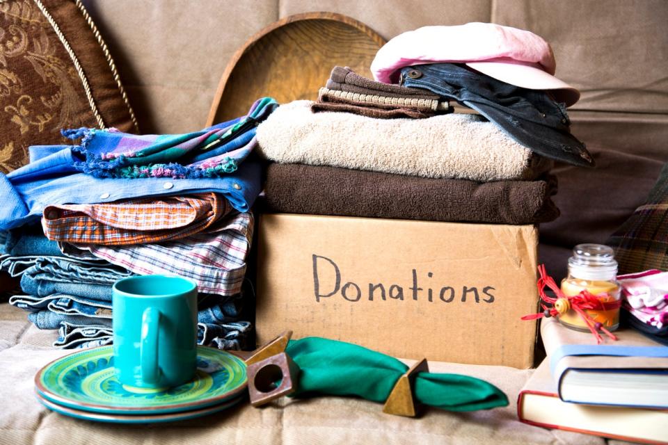 Gathering items to be donated to charity, including clothes, linens, and dishware.