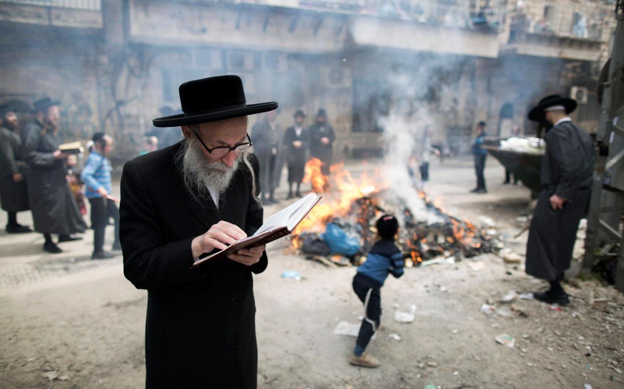 An Ultra-Orthodox Jewish man prays as leavened bread is burnt at Mea Shearim neighborhood in Jerusalem, Israel, 10 April 2017.  - ABIR SULTAN 