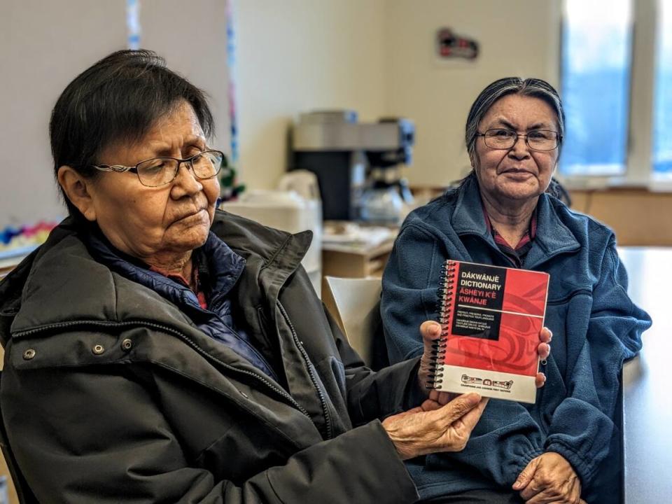 Lena Smith-Tutin and her sister Vivian Smith hold their Southern Tutchone dictionary at the Da Kų Cultural Centre in Haines Junction, Yukon. The sisters spent 7 years collecting basic and essential words to create the dictionary. (Virginie Ann / CBC News - image credit)