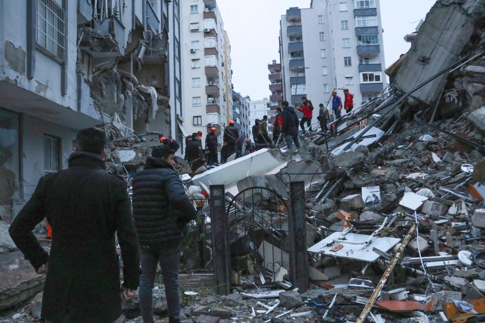 People and rescue teams try to reach trapped residents inside collapsed buildings in Adana, Turkey, Monday, Feb. 6, 2023.