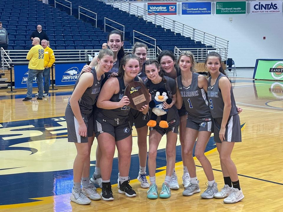 The Millbrook girls basketball team poses with its regional title plaque and make-believe mascot after beating Carle Place at Hofstra University on Saturday.