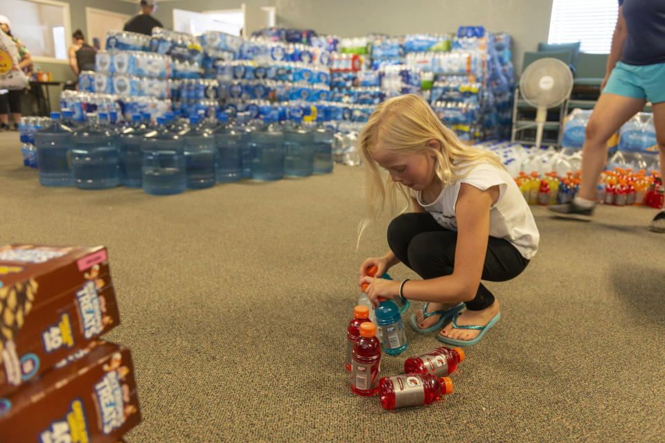 Teagan Clouse helps stack sport drinks at the Christian Fellowship of Trona, Calif., on Tuesday, July 9, 2019. The church received a large donation from a cooperative effort from several High Desert charities and businesses after two strong earthquakes struck Thursday and Friday last week. It could be several more days before water service is restored to the tiny town of Trona, where officials trucked in portable toilets and showers. (James Quigg/The Daily Press via AP)