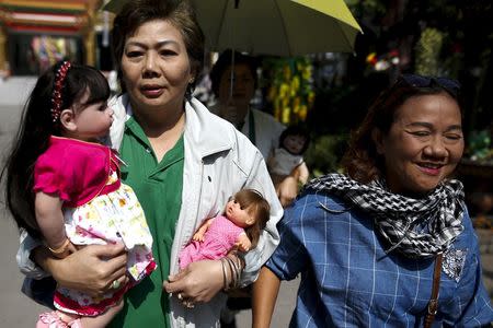 Women carry "child angel" dolls to a Buddhist monk to be blessed at Wat Bua Khwan temple in Nonthaburi, Thailand, January 26, 2016. REUTERS/Athit Perawongmetha